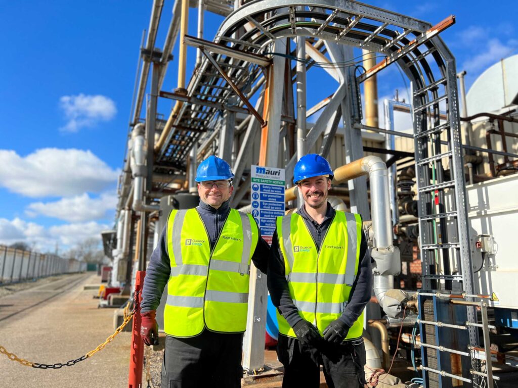 Two men in safety vests stand beside a large industrial plant, representing Fleetsolve's commitment to operational support.