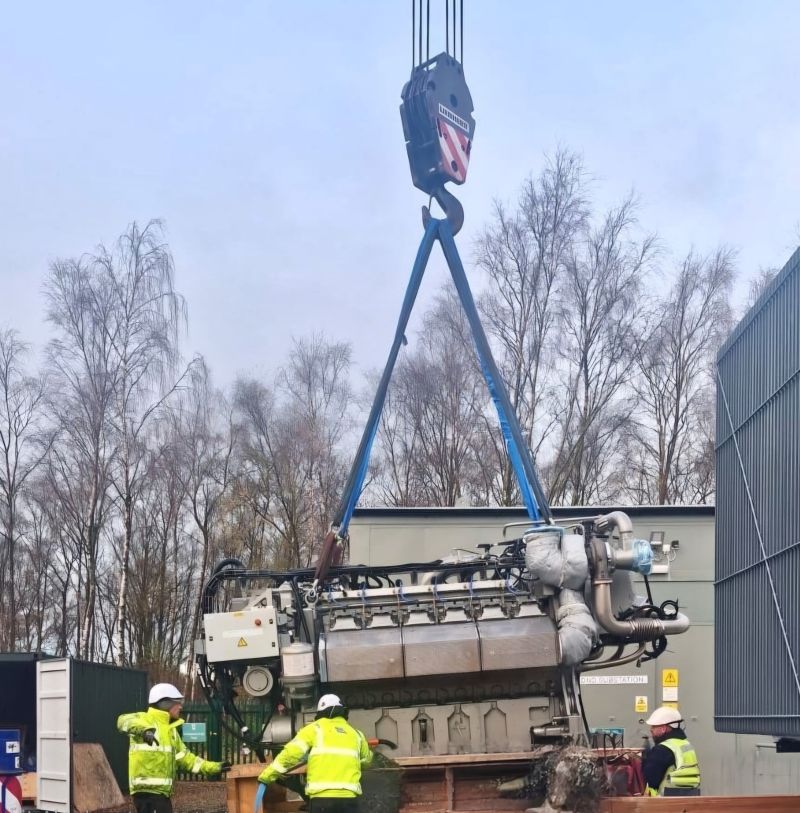 A crane lifts a large engine from a building, part of the Fleetsolve CHP System supply and maintenance process.