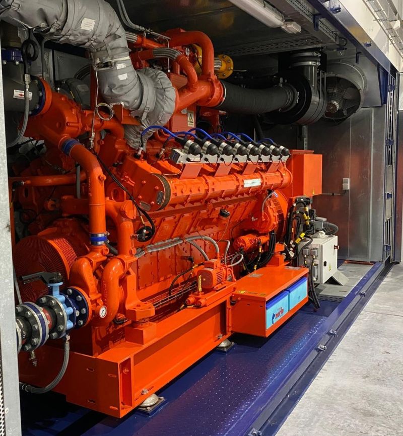 A large orange Guascor CHP engine is installed inside a building, showcasing its industrial design and functionality.